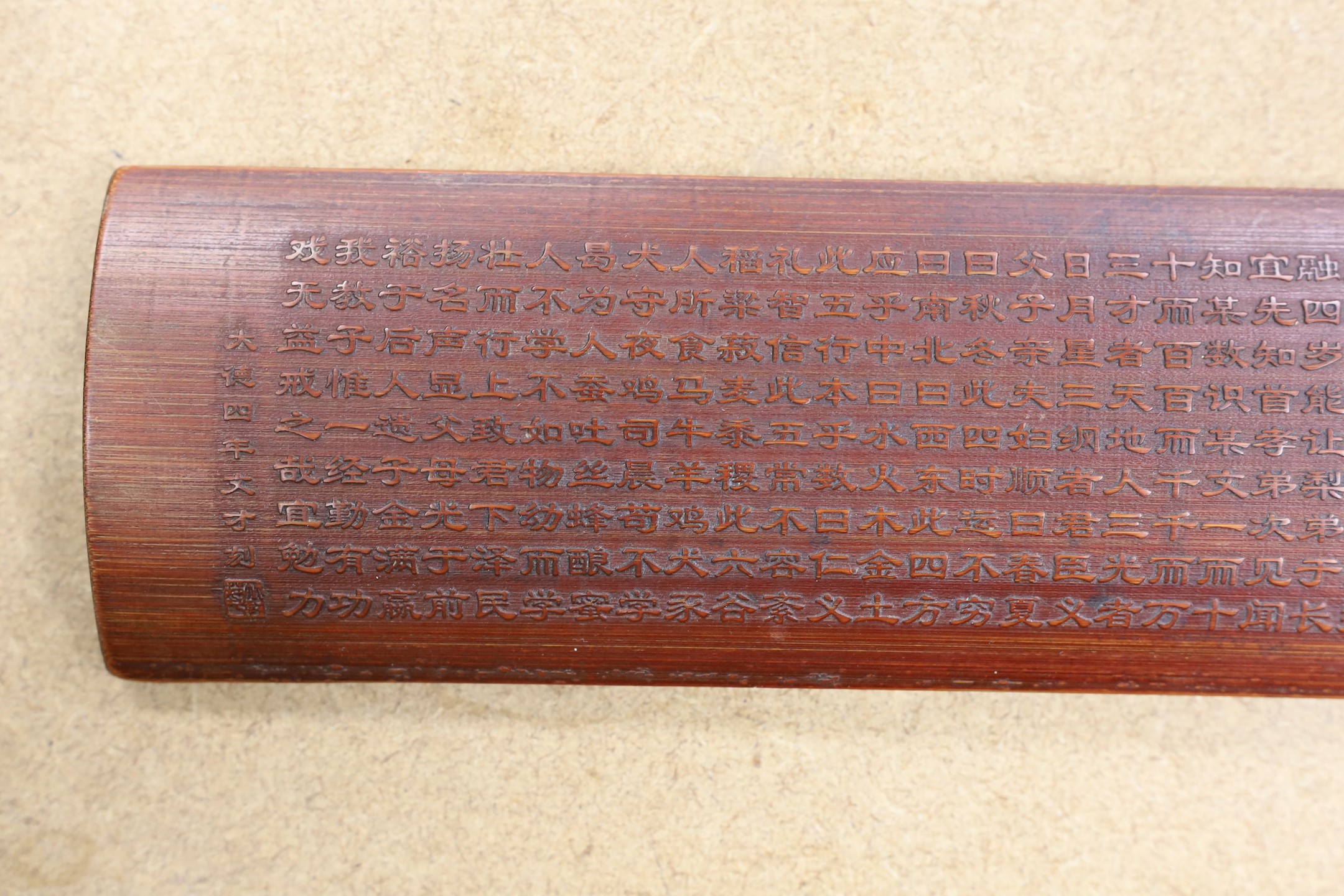 A Chinese bamboo inscribed wrist rest, carved in relief with columns of calligraphy, 30cm wide